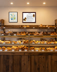 Display case with various pastries in a bakery setting, with a Basset Hound Heritage History   Portrait on the wall.